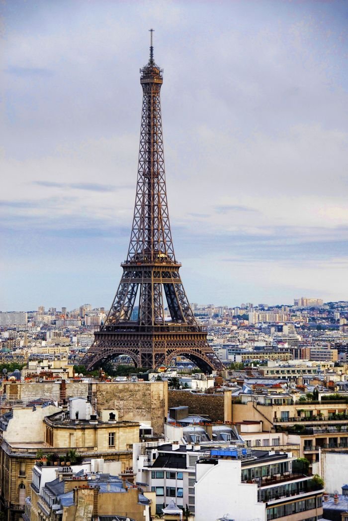 A captivating view of the Eiffel Tower international travel agency rising above the Paris cityscape under a cloudy sky.