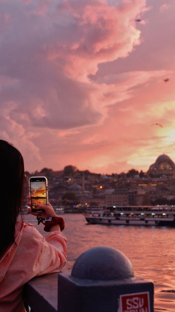 A woman captures the stunning Istanbul skyline at sunset with her phone best international travel companies