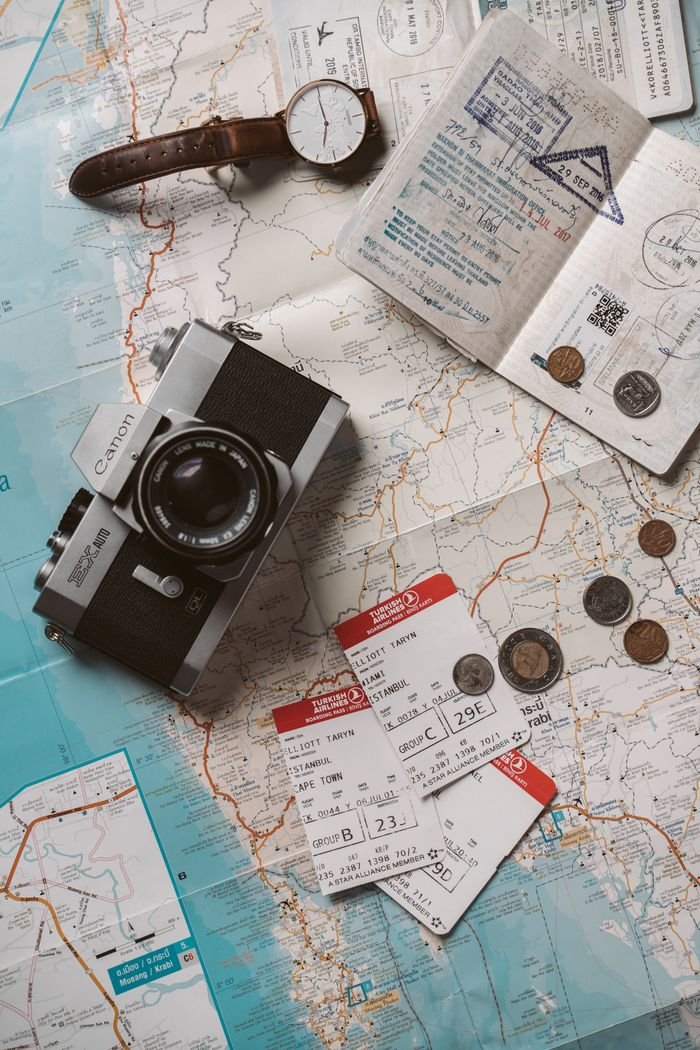 Flat lay travel essentials including passports, tickets, and a vintage camera on a world map foreign travel agency